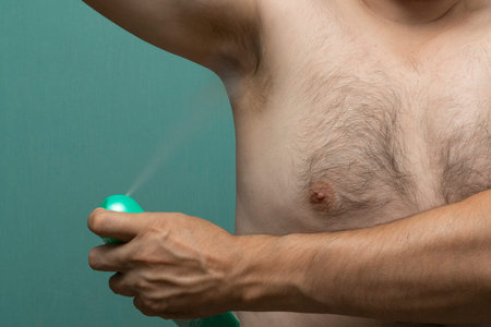 man uses deodorant spray from sweat and scent underarms