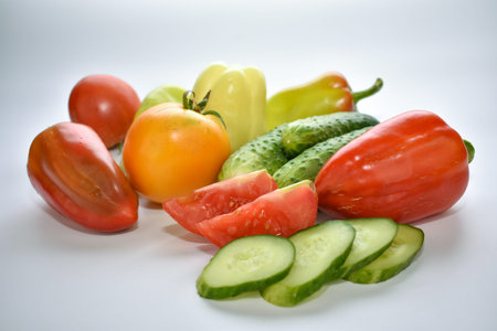 green cucumbers, red bell peppers and tomatoes on a white background, vegetable assortmentの写真素材