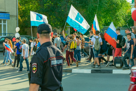 Russian policeman in uniform with a badge on the street at a rally of protest, view from the back...