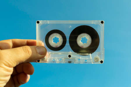 transparent audio cassette in hand on a blue backgroundの写真素材
