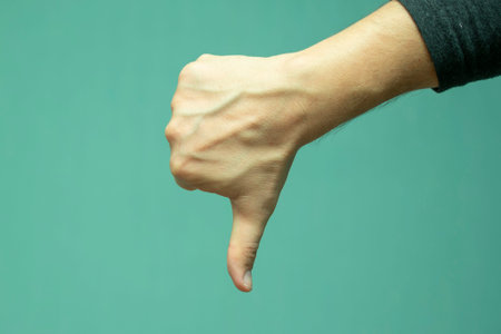 mans hand with a gesture showing disapproval, thumb down