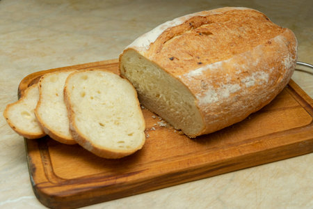 Sliced homemade bread on a cutting board on a wooden background.