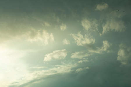 cloudy gray stormy sky with shining light from the setting sunの写真素材