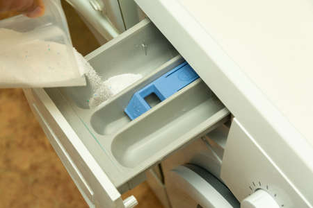 Woman pouring washing powder into the washing machineの写真素材