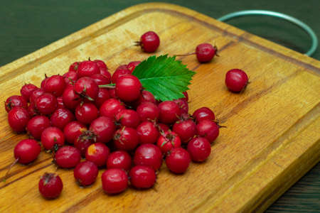 ripe red hawthorn berries on a kitchen board close-upの写真素材