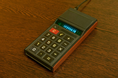 old vintage calculator on a wooden table, with green glowing numbers on display