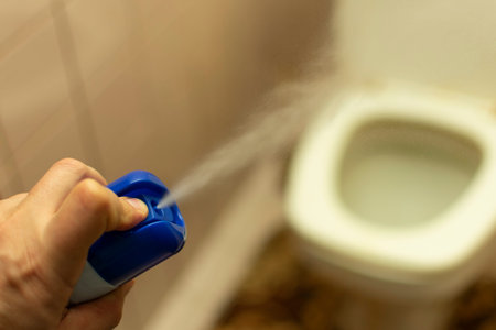 hand spray air freshener on the blurred background of the toilet, removing the unpleasant odor...