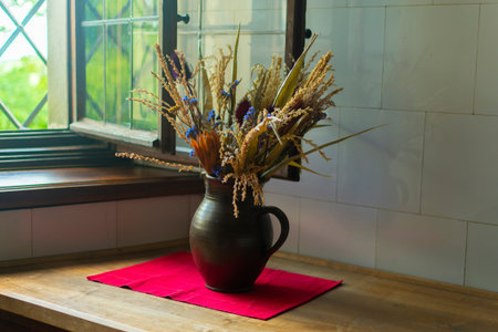 dry bouquet of evil and flowers in a vase on a red cupboard on the table, in the kitchenの写真素材