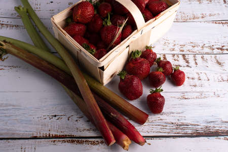 Strawberries and rhubarb freshly harvested, with a small wooden basketの写真素材