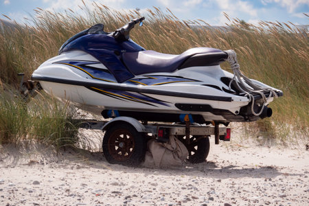 Jet ski on a transport trailer on the sandy beach in front of marram grass