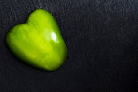 Heart-shaped pepper piece on a black slate plateの写真素材