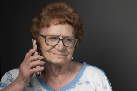 Head and shoulder portrait of an over 90-year-old lady smiling with a mobile