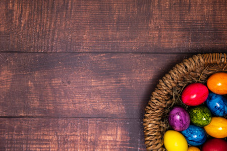 round easter basket with colorful easter eggs on rustic white wooden tabletop, tabletop