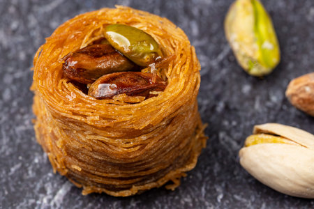 Close up of an angel hair nest with caramelized pistachios. Arranged on a sdchlack slate plate and...