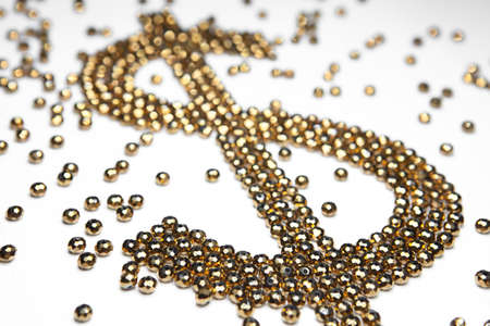 Dollar sign made of golden beads on white backgroundの写真素材