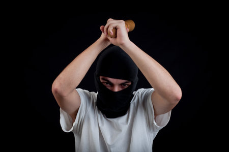 Hooligan with baseball bat ready for fight on black background