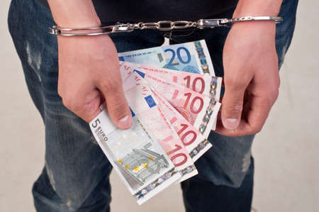 closeup of a man in handcuffs holding moneyの写真素材