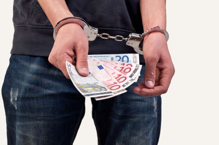 man in handcuffs is holding money over white backgroundの写真素材