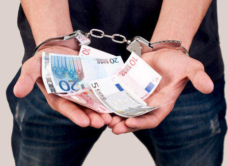 closeup of a man in handcuffs holding money