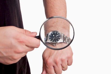 man with magnifier in hand looking at his watch on white background