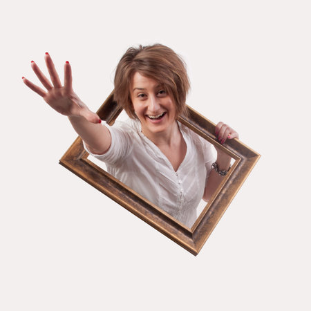 Funny beautiful woman coming out from a empty frameの写真素材
