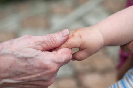 hands of baby grandson and old grandmother, concept of family relationship and passage of timeの写真素材