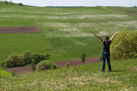Young woman on a meadow with arms raised enjoying summer sun and the fresh air, enjoying the nature
