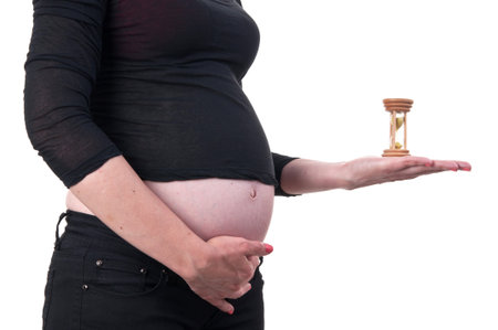 Image of a young pregnant woman holding an hourglass next to her belly
