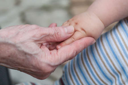 hands of baby grandson and old grandmother, concept of family relationship and passage of timeの写真素材