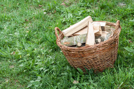 Basket of cut logs fire wood on green grass, environmental conceptの写真素材