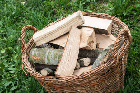 Closeup basket of cut logs fire wood on green grass, environmental conceptの写真素材