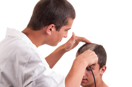 Barber cutting hair to a young man with clipper on white