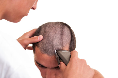 Barber cutting hair with clipper on white