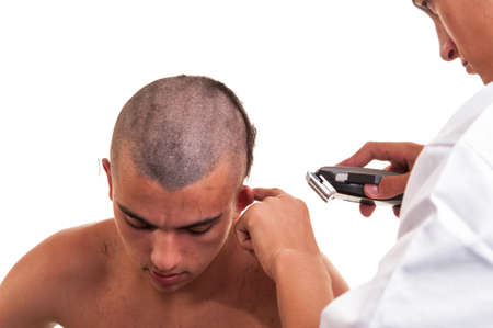 Barber cutting hair with clipper on white backgroundの写真素材