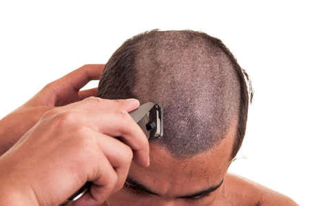 Man having a haircut with a hair clippers over a white backgroundの写真素材
