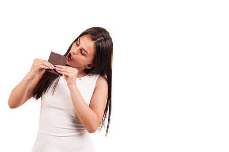 Young woman eating chocolate bar with lust on white background, copy spaceの写真素材