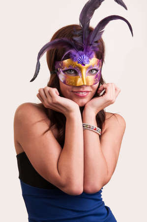 Beautiful young woman hides her beauty under purple mysterious venetian maskの写真素材