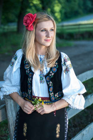 beautiful singer with flowers posing in traditional costume, romanian folkloreの写真素材