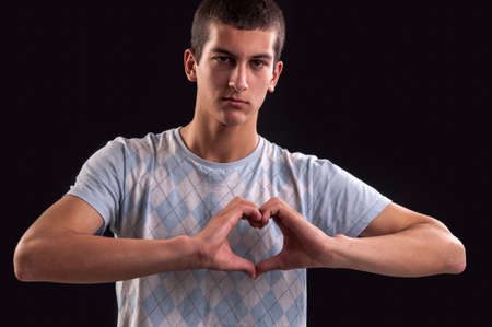 portrait of a young man doing a heart gestureの写真素材