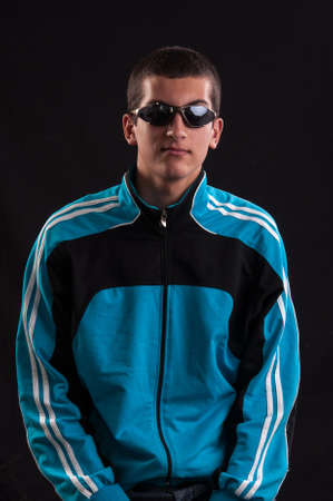 Fashionable young happy guy in sunglasses sitting in chairの写真素材