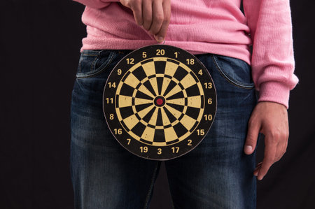 Teenager holding a dartboard with his hands