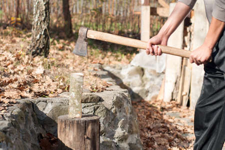 young man with an ax chops wood for heatingの写真素材