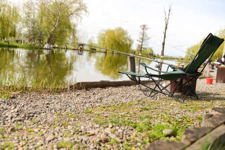 chair with fishing accessories at the shoreline on the lakeの写真素材