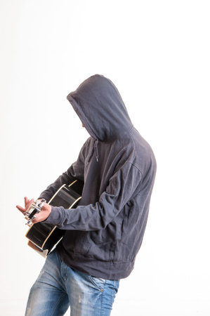 Sad teenager in hoodie playing acoustic guitar