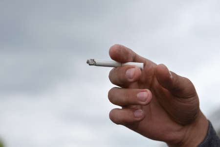man holding cigarette in his hand closeup outdoor. Cropped shotの写真素材