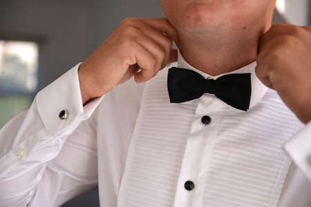 Mid section of happy groom adjusting his bow tieの写真素材
