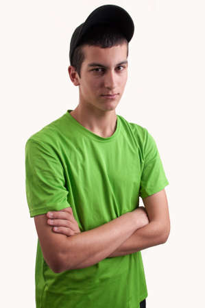 Portrait of a young man with arms crossed wearing a black cap on whiteの写真素材