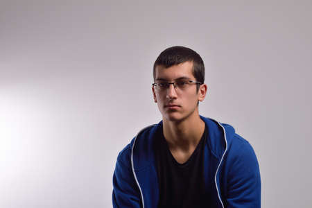 Sad teenager with blue sweatshirt standing against a dirty wallの写真素材