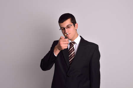 young man dressed in tuxedo lighting cigarette in studioの写真素材