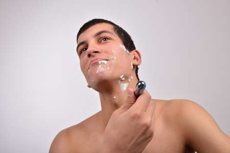 Handsome young man with lots of shaving cream on his face preparing to shave with razorの写真素材